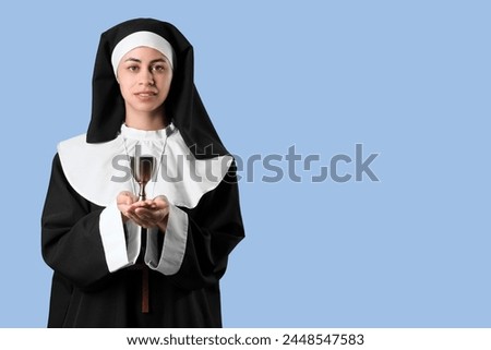 Young nun with chalice on blue background