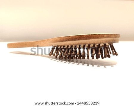 Brown wooden comb on white background. Photo taken from close up. Selective focus.