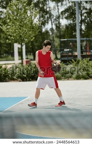 A young man stands on a basketball court, holding a ball in his hand, ready to play under the summer sun.