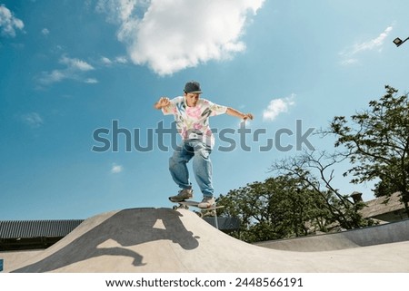 A young skater boy fearlessly rides a skateboard down the side of a ramp in a sunny outdoor skate park.