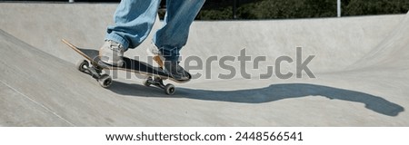 Young skater boy effortlessly cruises down the ramp on his skateboard at an outdoor skate park on a sunny summer day.