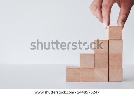 Hand stacking blank wooden cubes for put text,logo and infographic as a pyramid shaped on white table over white background with copyspace.