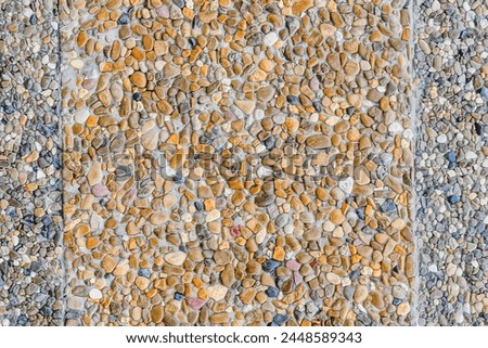 This is the photo of the building wall decorated by small grey and yellow stones. It's close up view of colorful stones