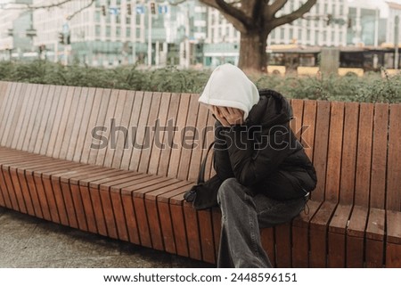 Upset and depressed girl holding smartphone and holding head. University sad student suffering from depression at high school. Lonely bullied teen. Royalty-Free Stock Photo #2448596151