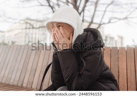 Upset and depressed girl holding smartphone and holding head. University sad student suffering from depression at high school. Lonely bullied teen. Royalty-Free Stock Photo #2448596153