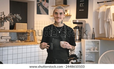 Handsome barista guy work coffee shop. Tattooed hipster man portrait. Happy male face smile. Joy young adult person look camera at cozy cafe house. Stylish dyed hair waiter make hot tasty drink order. Royalty-Free Stock Photo #2448610103