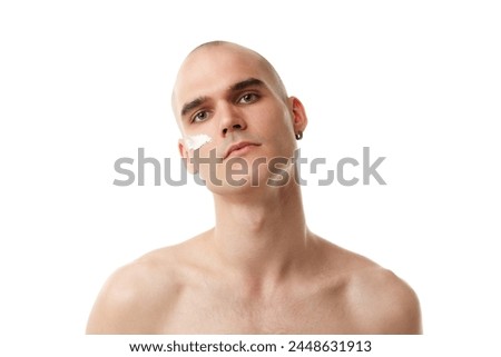 Handsome shitless young man with moisturizing cream on face isolated on white studio background. Spotless well-kept skin. Concept of skincare, male beauty, wellness, cosmetics, self-care Royalty-Free Stock Photo #2448631913