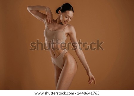 Creamy colored underwear. Woman with slim body shape is posing against background.