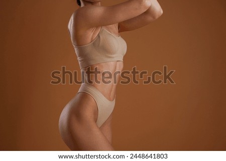 Fitness slim body shape. Woman is posing against background.