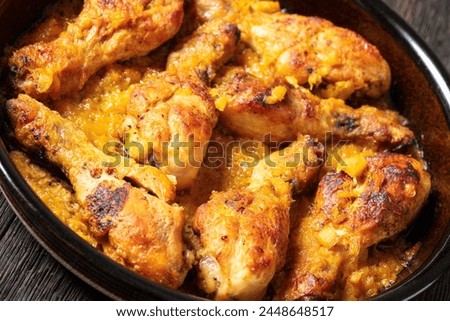 chicken drumsticks baked in crushed pineapple sauce in black dish on dark rustic wooden table, dutch angle view, close-up Royalty-Free Stock Photo #2448648517