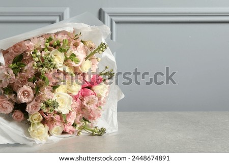 Beautiful bouquet of fresh flowers on table near grey wall, space for text