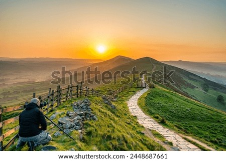 Landscape photographer at Mam Tor hill  in Peak District taking picture at sunrise