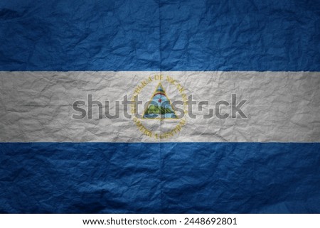 colorful big national flag of nicaragua on a grunge old paper texture background