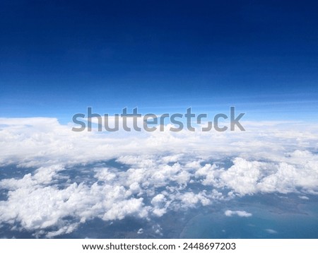 Wisps of clouds in a clear blue sky, taken from an airplane window.