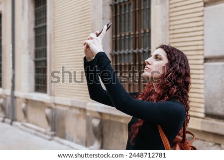 A tourist takes out her cell phone to take photos of buildings in the city she is visiting