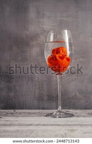 A comical skull face down trying to drown in a glass of water
