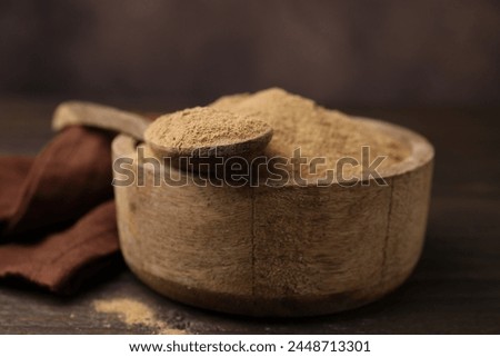 Dietary fiber. Psyllium husk powder in bowl and spoon on wooden table, closeup