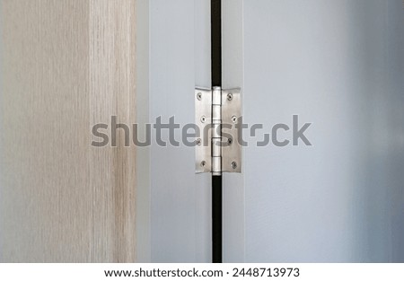 Stainless door mortised hinge on a white door and door frame with copy space. Royalty-Free Stock Photo #2448713973