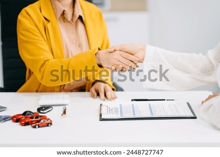 Asian people car salesman or sales manager offers to sell a car and explains of signing a car contract and signing car insurance document or lease paper.
