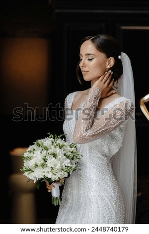 Captivating image of an elegant bride in white lace gown with bouquet, ideal for wedding magazine or website. Bride stands against black background, exuding sophistication and charm.