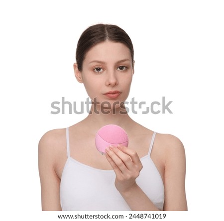 Washing face. Young woman with cleansing brush on white background