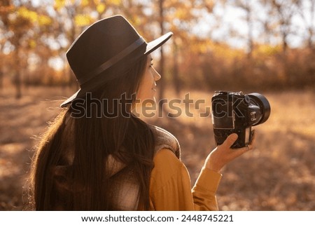 beautiful woman photographer taking photos in autumn forest using SLR camera. Copy space. Nature photographer concept