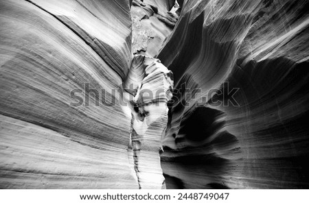 Walls of a slot canyon in Arizona, USA. Natural wonder, magic place and tourist attraction formed by the power of erosion. Sandstone washed out by water in wavy shapes. Black and white greyscale. Royalty-Free Stock Photo #2448749047
