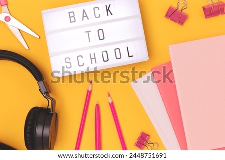 Back to school. Lightbox with letters, headphones and stationery on a yellow background.