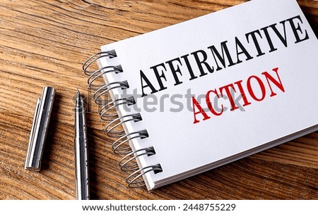 AFFIRMATIVE ACTION text on a notebook with pen on the wooden background . 