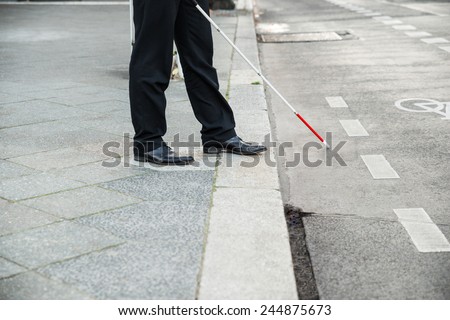 Low Section Of A Blind Person Crossing Street