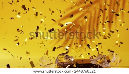 Image of confetti falling and cocktail on yellow background. Party, drink, entertainment and celebration concept digitally generated image.