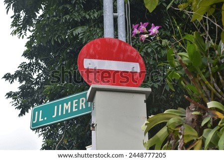 photo of stop sign on Jalan Jimerto, Surabaya. next to a purple orchid plant.