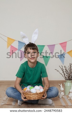 Easter photo shoot.A child holds a basket of Easter eggs in his hands.A boy wearing bunny ears sits on the floor.