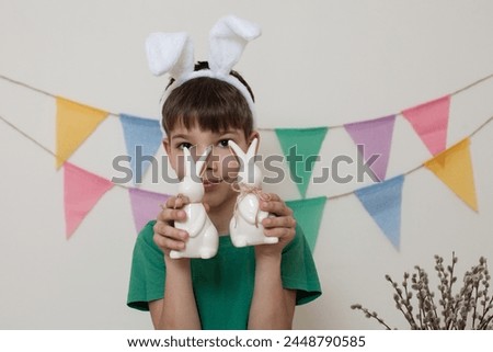 Easter photo shoot.A child holds an Easter bunny in his hands and smiles.Boy with rabbits in his hands.