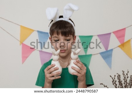 Easter photo shoot.A child holds Easter bunnies in his hands and looks at them close-up.Boy with rabbits in his hands.