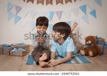 Children's birthday photo.Children take pictures for their birthday.Cheerful children laugh and hug.The boys are sitting next to boxes of gifts.