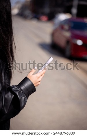 Young happy woman in black in the city with smartphone