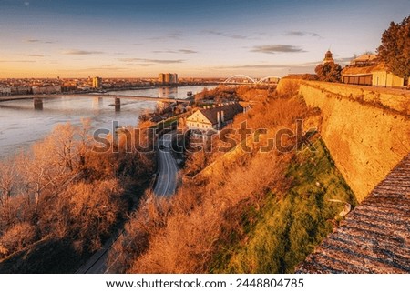 enchanting beauty of Novi Sad's skyline against the backdrop of the Danube River, showcasing the majestic fortress of Petrovaradin in the soft light