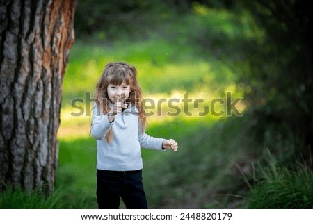 Cute blonde girl has fun blowing on the chicory plant in the park in the spring.