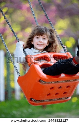 Cute blonde girl having fun swinging on a swing in the playground