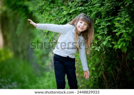 Cute blonde girl enjoying nature among green leaves in spring