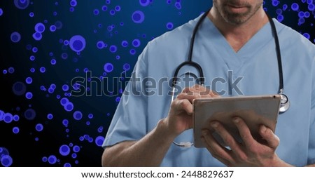 Image of midsection of caucasian male doctor over blue cells on navy background. Human biology, anatomy and medicine concept digitally generated image.