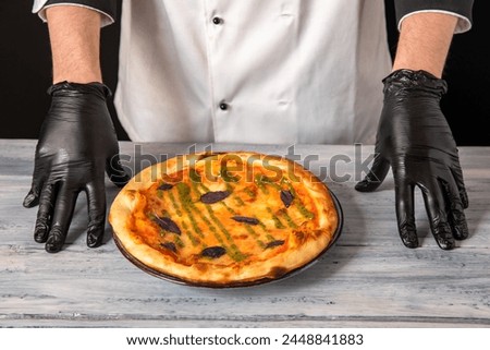 Chef presenting pizza, studio background, culinary concept, stock photo