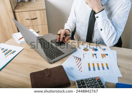 Man working on his laptop in the office, making calculations, business concept, stock photo
