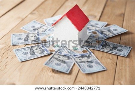 Wooden decorative house, banknotes around, apartment buying, selling concept stock photo