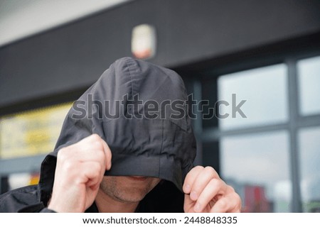 a naive man hides his face under a hood. anonymity, secrecy, personal space Royalty-Free Stock Photo #2448848335