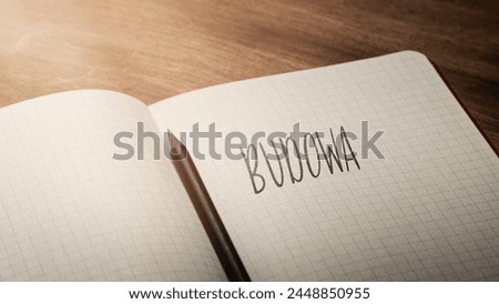 A handwritten inscription "Budowa" on a grille of an open notebook on a wooden countertop, next to a black pencil, lighting of light. (selective focus), translation: Construction