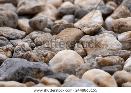 Picture on a floor consisting of different sized and colored stones in daylight