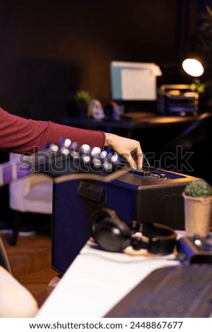Sound producer adjusting volume levels on home studio amplifier before recording guitar tunes for mixing and mastering session. Male composer creating a new song with stereo gear. Close up.