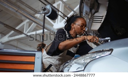 Licensed repairman in repair shop using torque wrench to tighten screws after checking car parameters during maintenance. Expert using professional tool in garage to mend vehicle, close up shot Royalty-Free Stock Photo #2448867777
